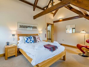 Ein Schlafzimmer mit einem hölzernen Bett, Nachttischen, einem Spiegel und einem roten Sessel.