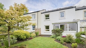 A two-story residential building with a well-maintained garden, a conservatory, and a visible garage. - 2 Bed in Keswick (oc-sz188) (Keswick)