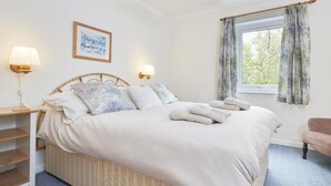 A neatly made bed with pillows and towels, a bedside lamp, a framed picture on the wall, and a window with curtains. - 2 Bed in Keswick (oc-sz188) (Keswick)