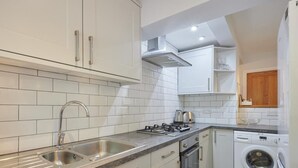 A modern kitchen with white cabinets, a stainless steel sink, a gas stove, an oven, and a built-in washing machine. - 2 Bed in Keswick (oc-sz019) (Keswick)
