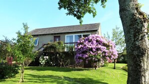 A house with a well-maintained lawn and a large flowering tree in the front yard. - 1 Bed in Kirkby-in-furness (oc-sz463) (Kirkby Ireleth)