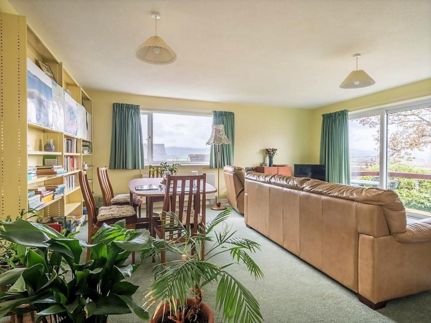 A living room with a sofa, dining table, chairs, and a bookshelf.