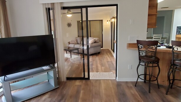 A living room with a TV, a sofa, and a coffee table. There is a sliding door leading to another room. - Bicycles, fishing poles and lap tops invited! (Inverness)