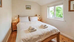 Una camera da letto con un letto in legno, due comodini con lampade, una finestra con vista sul verde e un quadro appeso al muro.