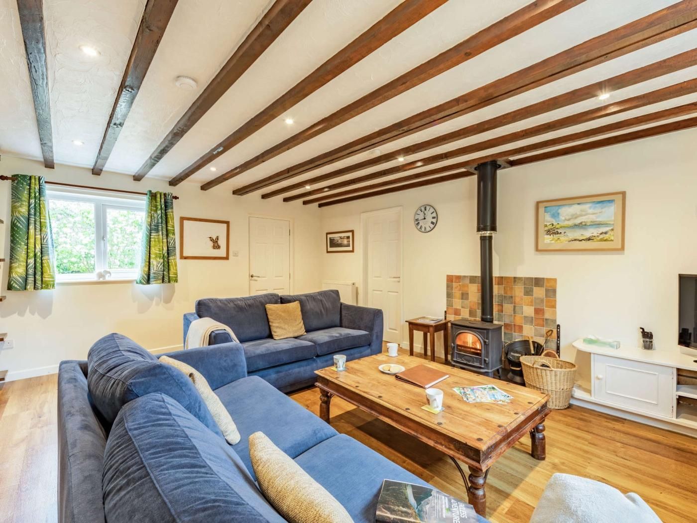 Een woonkamer met een zithoek, een houten salontafel, een open haard en een televisie.