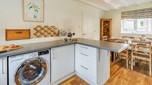 Una cucina compatta con lavatrice, radio e zona pranzo con mobili in legno.