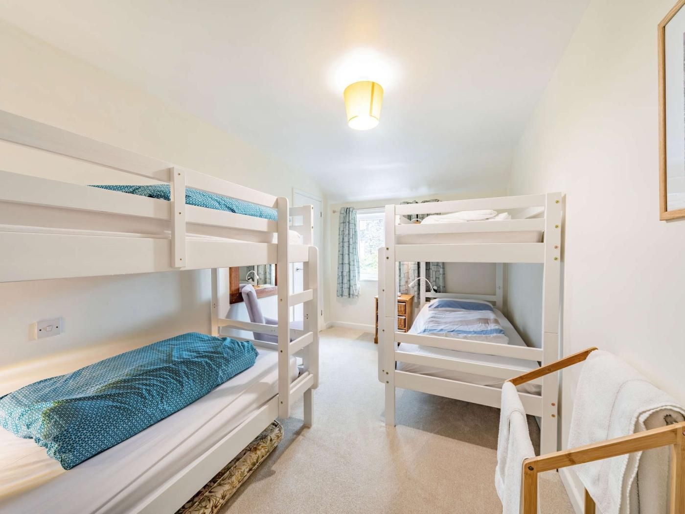 Une chambre avec un lit superposé, une fenêtre, une table de chevet et un luminaire suspendu.