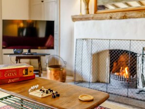 A cozy living room with a fireplace, a Scrabble board, and a television. - 5 Bed in Ulverston (oc-sz587) (Broughton Beck)