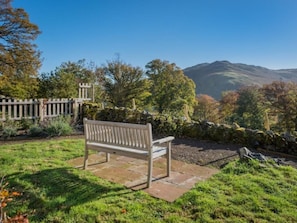 A bench in a garden with a stone wall and trees. - 4 Bed in Penrith (oc-sz367) (Dockray)