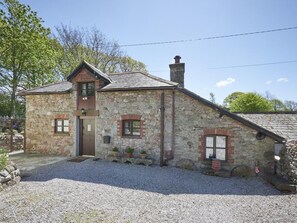 Ein Haus aus Stein mit einem geneigten Dach, einem Schornstein und einer Zuwegung mit Kies.