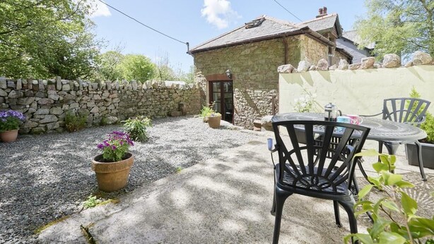 A stone building with a gravel patio, a stone wall, and potted plants. - 1 Bed in Holmrook (oc-sz471) (Irton with Santon)