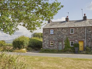 A stone house with a yellow door, a chimney, and a small window. - 2 Bed in Holmrook (oc-sz205) (Irton with Santon)