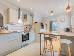 Eine moderne Küche mit weißen Schränken, Edelstahlgeräten und einer Holztheke mit Barhocker.