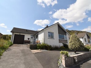 Ein zweistöckiges Haus mit Garage, einer Veranda mit Bänken und einer Auffahrt zur Garage.