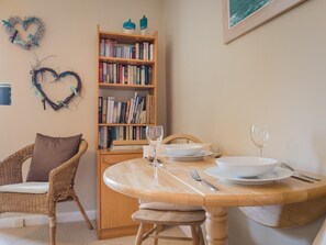 A dining area with a wooden table set for two, a wicker chair, a bookshelf, and heart-shaped decorations on the wall. - 1 Bed in Penrith (oc-sz222) (Hutton)