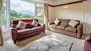 A room with two sofas, a chandelier, and a view of the outdoors. - 3 Bed in Keswick (oc-sz249) (Keswick)