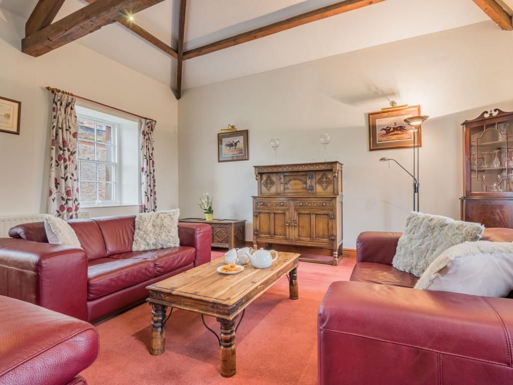 A living room with a red leather sofa, a wooden coffee table, and a cabinet.