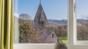 Een uitzicht op een kerk met een puntige ingang en een klokkentoren, gezien door een raam.