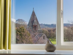 Blick durch ein Fenster auf eine Kirche mit einem Spitzspitzboden und einem Glockenturm.
