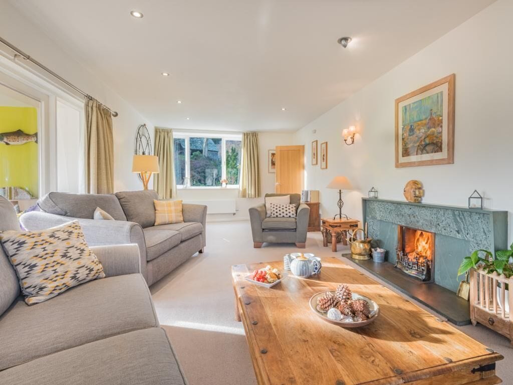A living room with a sofa, armchair, coffee table, fireplace, and a painting on the wall.