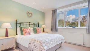 Een slaapkamer met een bed, twee nachtkastjes, een raam met gordijnen en uitzicht op buiten.
