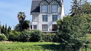 Ein zweistöckiges Haus mit einem geneigten Dach, großen Fenstern und einem Balkon.