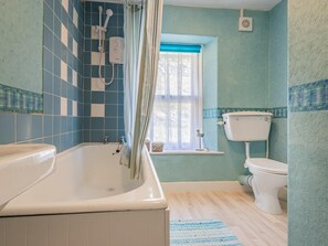 Ein Badezimmer mit Badewanne, Toilette und Fenster.