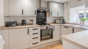 Uma cozinha moderna com armários brancos, forno embutido, micro-ondas e torradeira.