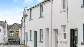Une rue étroite bordée de bâtiments blancs, un café appelé « George Fisher Café » au bout, et un bâtiment traditionnel surmonté d’une tour horloge.