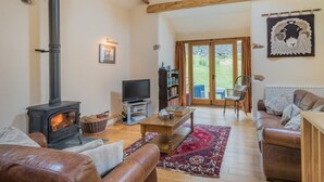 A cozy living room with a fireplace, leather sofas, a television, and a bookshelf. - 2 Bed in Penrith (oc-sz470) (Patterdale)