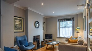 A living room with a sofa, armchair, and a television. - 3 Bed in Keswick (oc-sz029) (Keswick)