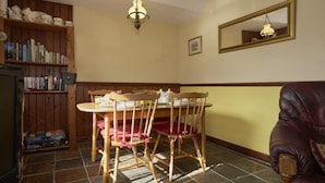 A dining area with a wooden table and chairs, a bookshelf, a mirror, and a leather armchair. - 2 Bed in Wasdale Head (oc-sz551) (Wasdale)