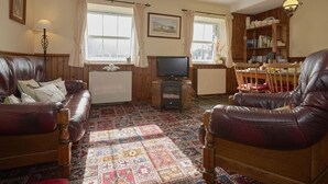 A cozy living room with a fireplace, leather sofas, a television, and a bookshelf. - 2 Bed in Wasdale Head (oc-sz551) (Wasdale)