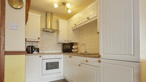 A kitchen with white cabinetry, a stove, a sink, and a ceiling light fixture. - 2 Bed in Wasdale Head (oc-sz551) (Wasdale)