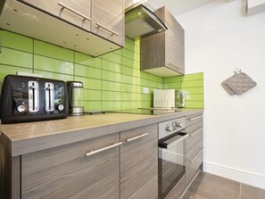 Eine moderne Küche mit grüner Fliesenrückwand, eingebautem Toaster, Kaffeemaschine und Mikrowelle.