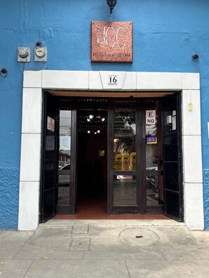 A hotel entrance with a blue exterior, a numbered sign, and a sign prohibiting smoking.