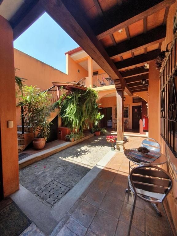Un patio con un área de estar cubierta, plantas en macetas y una escalera que lleva a un nivel superior.