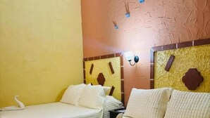 Two single beds with white bedding, a wall clock, and a decorative wall panel.