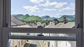A window view of a street with buildings and mountains in the background. - 1 Bed in Keswick (oc-sz166) (Keswick)