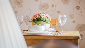 A dining table with a floral arrangement, white plates, and glasses. - 1 Bed in Keswick (oc-sz166) (Keswick)