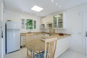 A modern kitchen with white cabinets, a granite countertop, and a built-in oven. - Beautiful Apt 450m From Lagoa da Conceicao Crm0201 (Florianópolis)
