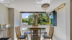 A room with a large window, a chandelier, and a table with chairs. - Beautiful Apt 450m From Lagoa da Conceicao Crm0201 (Florianópolis)