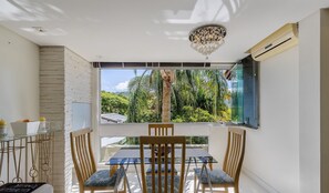 A room with a large window, a chandelier, and a table with chairs. - Beautiful Apt 450m From Lagoa da Conceicao Crm0201 (Florianópolis)