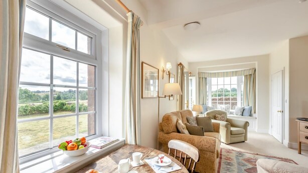 A room with a dining table set for breakfast, a sofa, and a view of the outdoors. - 1 Bed in Penrith (oc-sz176) (Lazonby)
