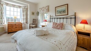 A bedroom with a bed, a wooden dresser, a chair, a nightstand, and a window with curtains. - 1 Bed in Penrith (oc-sz176) (Lazonby)