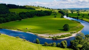 A river meandering through a lush green landscape with rolling hills and a clear sky. - 1 Bed in Penrith (oc-sz176) (Lazonby)