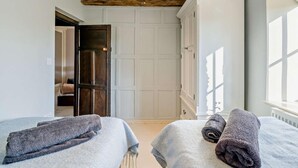 A bedroom with two beds, a wooden ceiling beam, a white wardrobe, and a window with blinds. - 4 Bed in Sedbergh (oc-sz595) (Millthrop)