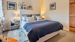 Ein Schlafzimmer mit einem Bett, Nachttischen, einer Lampe, einem Regal mit Dekoration und einer Holztür.