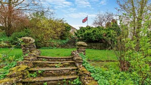 A stone staircase leading up to a flag, surrounded by greenery and a stone wall. - 1 Bed in Kirkby Stephen (oc-sz355) (Newbiggin-on-Lune)