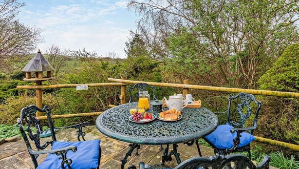 An outdoor dining area with a round metal table, two chairs, and a rustic fence. - 1 Bed in Kirkby Stephen (oc-sz355) (Newbiggin-on-Lune)